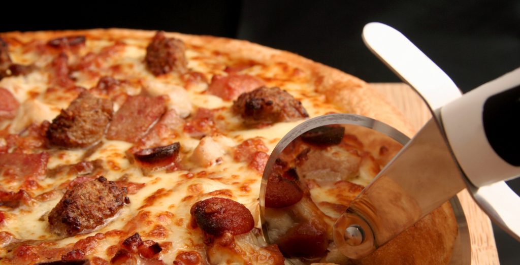 PAN-PIZZA-WITH-PEPPERONI-SAUSAGE-AND-HAM-GETTING-SLICED